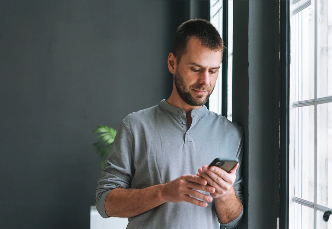 young bearded man with smartphone in hands reading utc